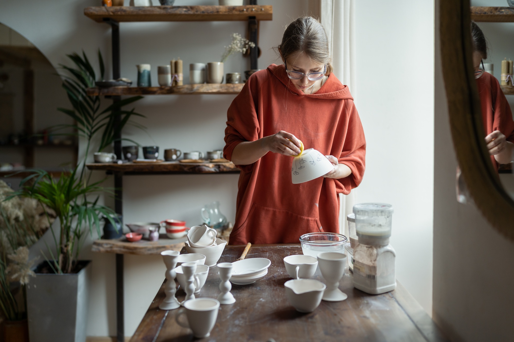 Creative woman molding clay bowl in studio. Concentrated female artist work on pottery in workshop